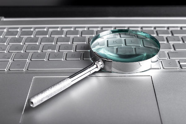 image of a magnifying glass laid over a silver keyboard
