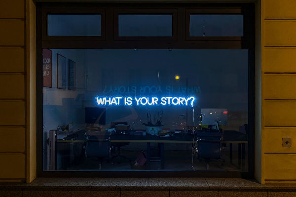 neon sign reading what is your story?