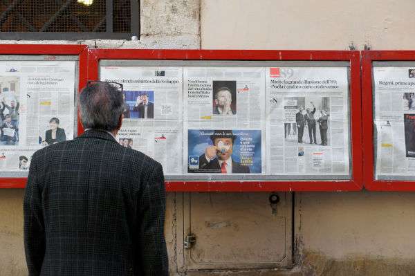 man looking at boxes displaying newspaper front pages